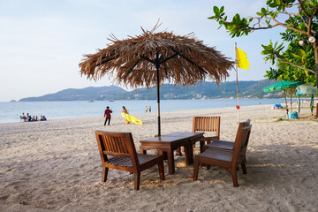 Patong beach, Thailand, February 2021. Beach chairs and umbrella made of straw and bamboo at beautiful tropical sea beach