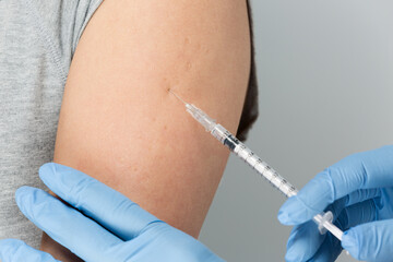 女性の腕に注射を打つ