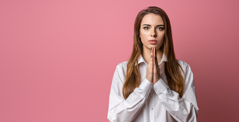 Attractive brunette girl prays for wellness of family, keeps palms pressed together in praying gesture, saying namaste