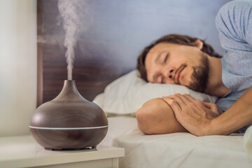 Aromatherapy Concept. Wooden Electric Ultrasonic Essential Oil Aroma Diffuser and Humidifier. Ultrasonic aroma diffuser for home. Man resting at home