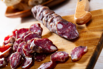 Traditional French thin dry cured sausage sliced on wooden surface