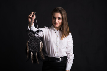 Young girl holding dreamcatcher in her arms in studio on black background