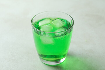 Glass of green soda on white textured background