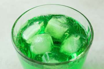 Glass of green soda on white textured background, close up