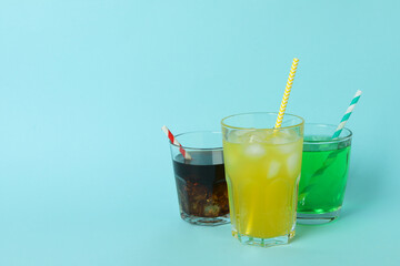 Glasses of different soda on blue background