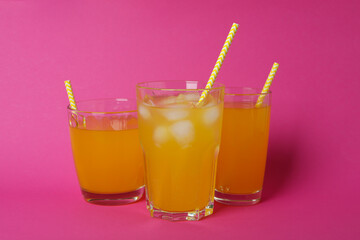 Glasses of orange soda on pink background