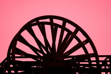 Abstrakte Aufnahme eines Rads in einer Industrieanlage mit einem rosafarbenen Hintergrund. Silhouette eines Rades.