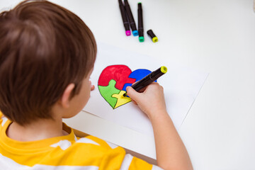 World Autism Awareness day. Children's hand draws heart from multi-colored puzzles. Mental health...