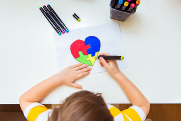 World Autism Awareness day. Children's hand draws heart from multi-colored puzzles. Mental health care concept