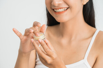 beautiful young asian woman applying cosmetic cream on her face. lip balm - obrazy, fototapety, plakaty