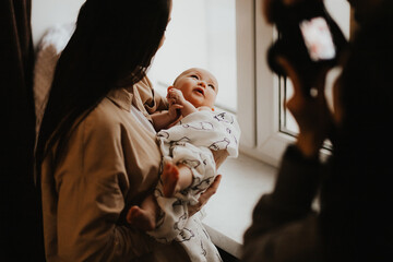 Loving mom carying of her newborn baby at home. Cute candid portrait of happy mum holding sleeping...