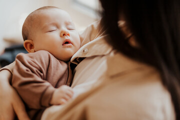 Loving mom carying of her newborn baby at home. Cute candid portrait of happy mum holding sleeping...