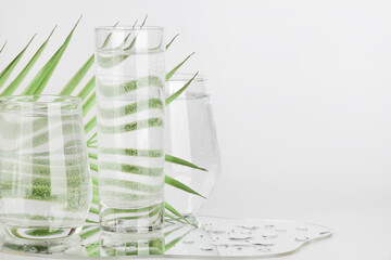palm leaf distorted through water in glasses with mirror on white background. pure water , relax ,...