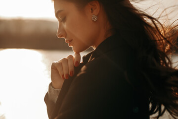 Tender thoughtful woman standing on lakeside