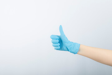 Hand of surgeon in blue medical glove showing a thumb up