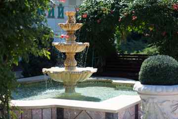A functioning fountain in the Greek style against the backdrop of greenery.