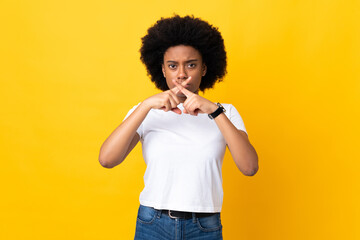 Fototapeta na wymiar Young African American woman isolated on yellow background showing a sign of silence gesture