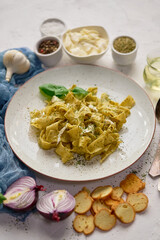Cooked homemade pasta with pesto, fresh basil, mozarella cheese and herbs