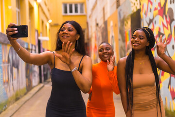 Three girls taking a selfie. Fashionable urban style with three black African girls on a city street, tight dresses. Girlfriends lifestyle