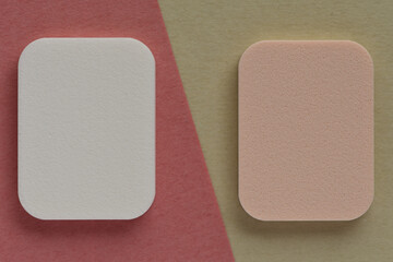 Makeup sponge isolated on pink and beige background.