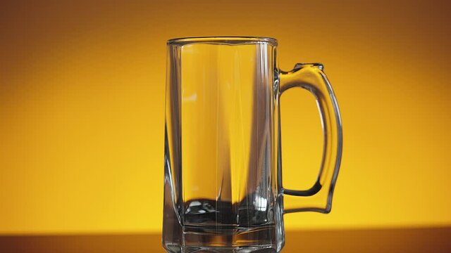 Slow motion shot of empty beer glass on orange background