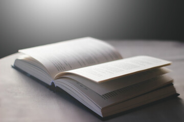 Side view of open book lies on table with white tablecloth on black background  