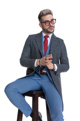 seated cool businessman rubbing his palms and looking away