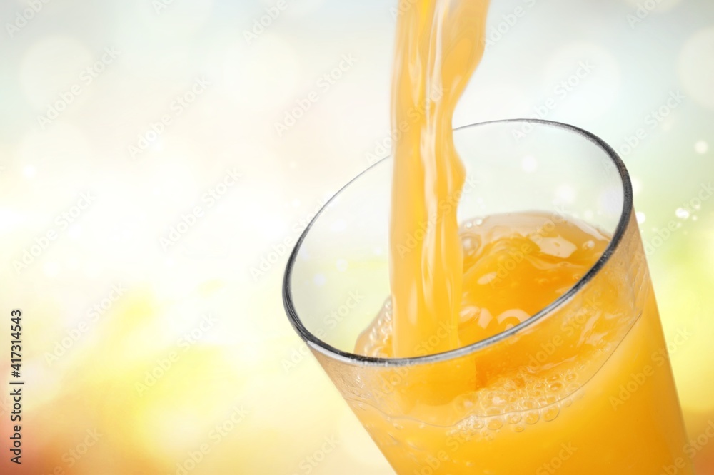 Poster orange juice pouring in glass on background