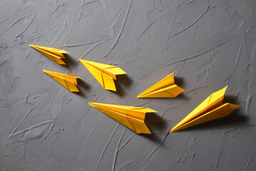 Yellow paper airplanes flying out  on a gray background