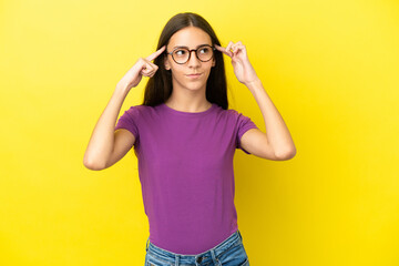 Young French woman isolated on yellow background having doubts and thinking