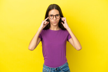 Young French woman isolated on yellow background frustrated and covering ears
