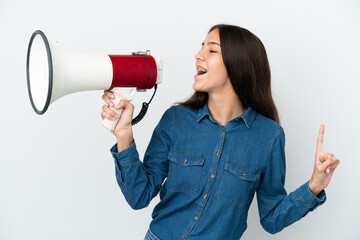 Young French girl isolated on white background shouting through a megaphone to announce something in lateral position