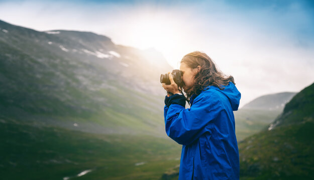 Young woman photographer traveling taking pictures of landscapes in the mountains