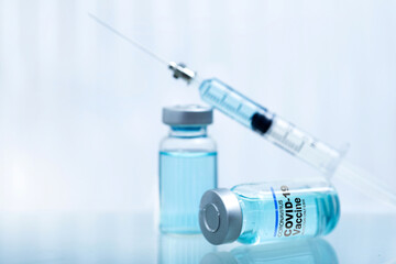 Bottle vial of Covid-19 coronavirus vaccine and syringe injection on white surface and white background, healthcare and medical concept, selective focus