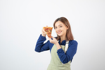 Portrait of woman in apron posing with slice of pizza on white background