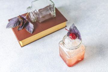 Picnic smash. Refreshing cold summer cocktail with grapefruit and  garnish by violet red basil leaves and cherry. Served in glass jar with crashed ice.