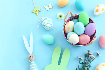 Cute bunny next to easter colorful eggs over pastel background