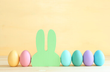 Cute bunny next to easter colorful eggs over pastel background