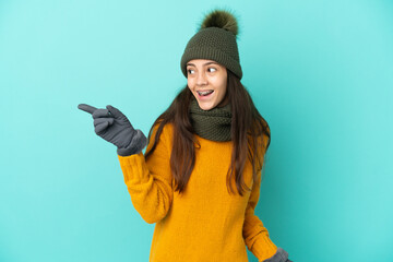 Young French girl isolated on blue background with winter hat intending to realizes the solution while lifting a finger up