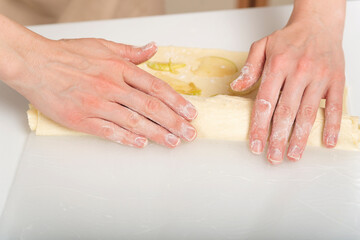 Hands of chef prepares an apple roll. Process of making an apple dessert.