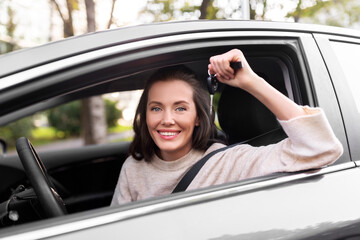 driving, safety and people concept - young woman or female driver sitting in car and showing key