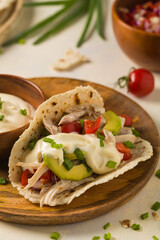 Mini tortillas with tomato salsa, avocado and boiled chicken. Front view.
