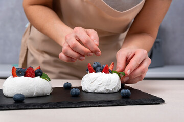Obraz na płótnie Canvas Process of making berry cake. Womens hands decorate meringue. Anna Pavlova cake