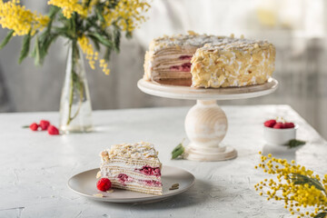 Napoleon puff cake with berry filling on a wooden stand with a cut piece on a plate.
