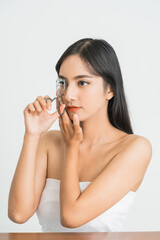 Naklejka premium Beautiful young asian woman with eyelash curler on white background