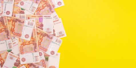 Banknotes with a face value of five thousand Russian rubles on a yellow background. Top view, free space for text