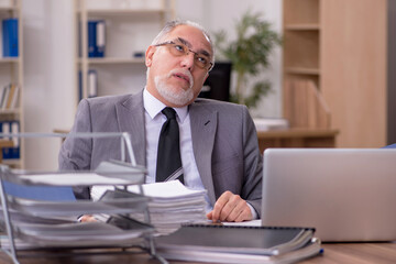 Fototapeta na wymiar Old male employee unhappy with excessive work in the office