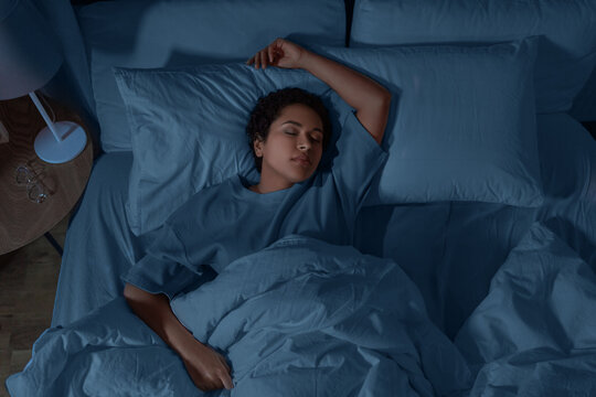 people, relax and comfort concept - young african american woman sleeping in bed at home at night