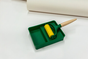 Yellow and green brush roller paint tray isolated on white background.