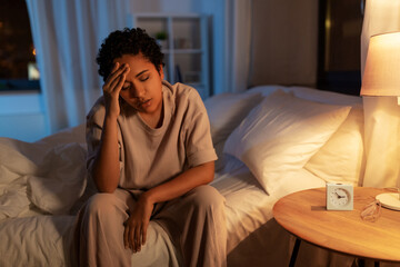 people, bedtime and rest concept - stressed african american woman having headache in bed at night